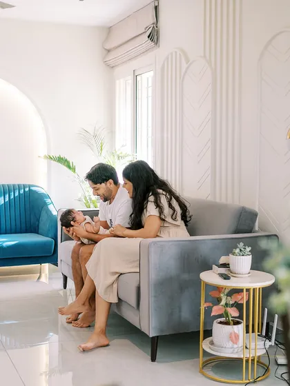 A wide shot of a family with their newborn on the sofa, showing how I use your home's environment to create natural and comfortable portraits.