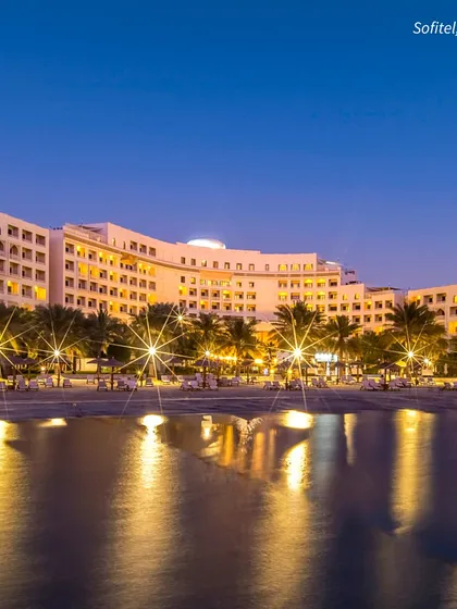 The Sofitel Bahrain at night, with its lights reflecting on the water. A beachfront destination wedding offers a magical ambiance that is simply unparalleled.