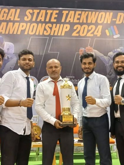 Coaches and senior members with a championship trophy, celebrating a team victory.