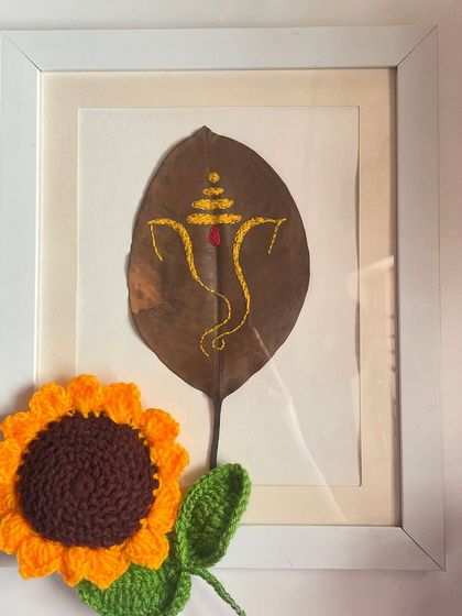 Ganpati Bappa Morya. This is a piece of my hand embroidery art on a dried peepal leaf, framed for home decor. The golden thread outlines Ganpati, creating a simple yet divine piece for any space.