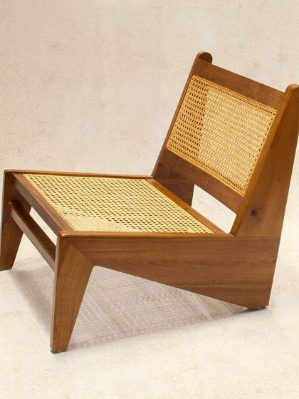 The 'N Chair' is a modern, low-slung lounge chair. Its angular solid teak frame and cane-woven surfaces make it a bold statement piece for contemporary interiors.