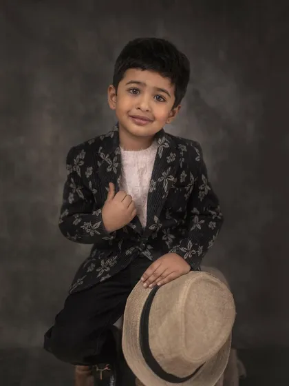 A classic, painterly portrait of a young boy, styled to create a timeless piece of art. My focus is on capturing their genuine expression, creating a portrait that feels both grand and deeply personal.