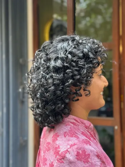 Showcasing the beauty of natural silver curls with a chic short haircut. This style is all about embracing texture and creating a sophisticated shape.