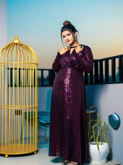 The model's pose highlights the details of the makeup and the elegant cut of the purple sequin dress.