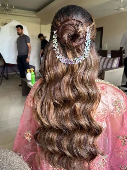 A romantic half-updo featuring a looped bun and long, flowing waves. The delicate, jeweled hair vine adds a touch of ethereal beauty.
