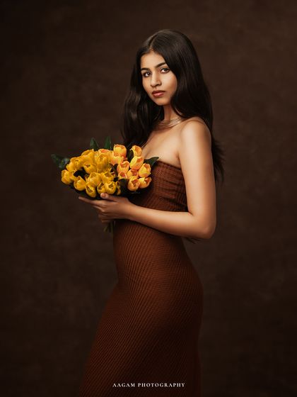 A classic portrait pose with a bouquet of yellow flowers, adding a subtle pop of color to the warm, earthy palette.