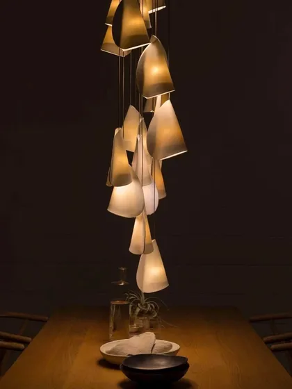 A small, intimate cluster of Bocci 21 pendants over a dining table. The light filtering through the thin porcelain creates a warm and inviting atmosphere, perfect for quiet dinners.