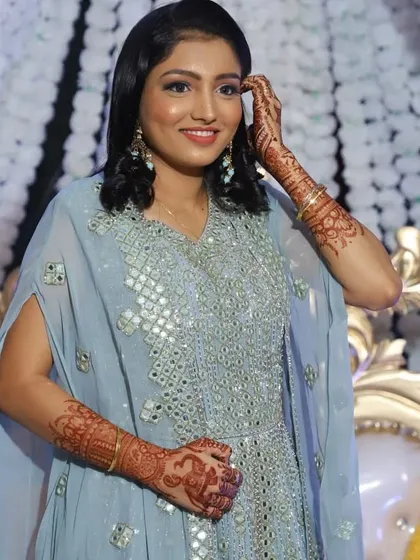 A happy client showing off her party-ready look. Her makeup is soft and glowing to complement the mirror work on her dress, and you can see the peacock and elephant motifs in her mehendi.