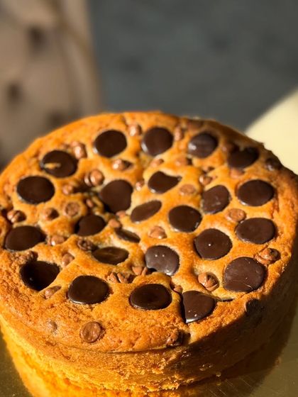 A finished butter cake, ready to be enjoyed. The golden-brown top and generous chocolate chips make it irresistible.