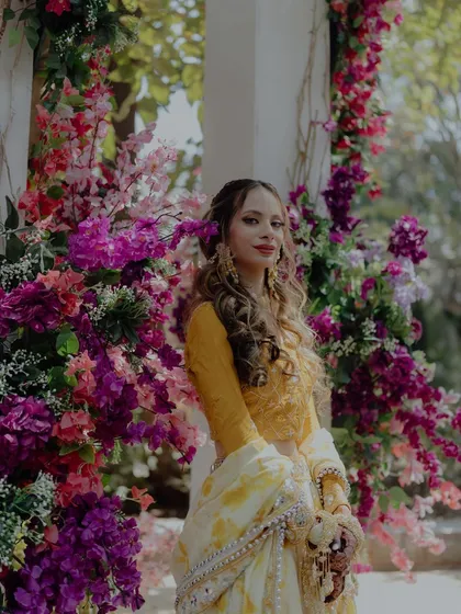 A beautiful portrait of the bride at her Mehendi, her yellow and white lehenga perfectly complementing the vibrant floral decor.