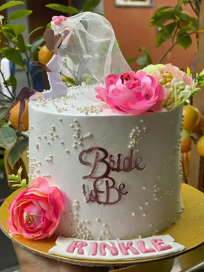 An elegant "Bride to Be" cake with a beautiful silhouette topper and flowers.