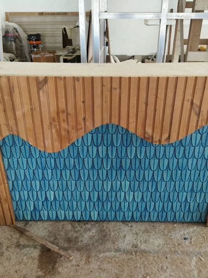 A custom-built counter combining natural wood cladding with a vibrant, fish-scale patterned tile inlay. This piece was crafted in our workshop for a client.