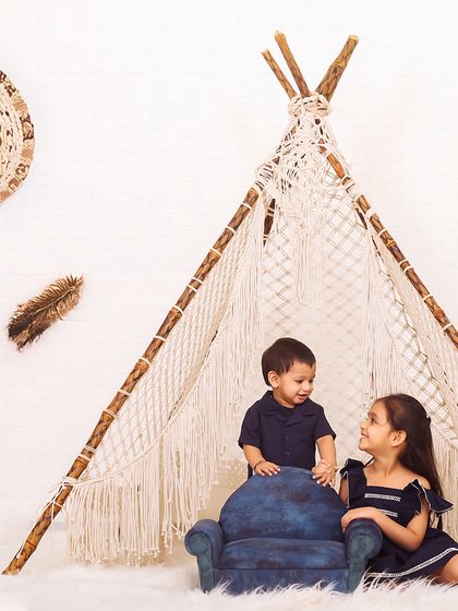 A candid moment of interaction between siblings. The older sister shares a smile with her younger brother in this adorable sibling photoshoot with a boho theme.