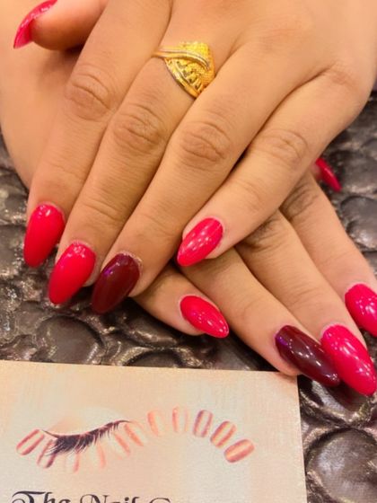 A sophisticated set of almond nails featuring two different shades of red. The mix of a bright, cherry red and a deeper maroon creates a subtle and stylish contrast.