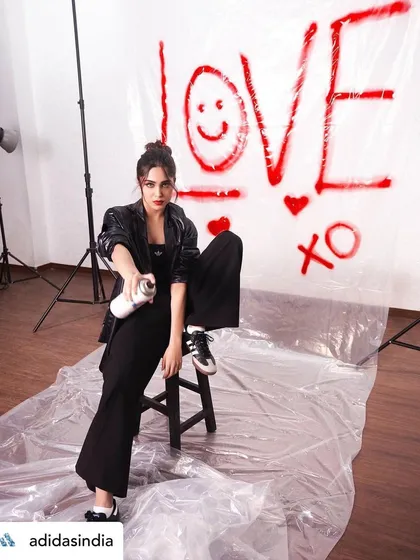 Sharvari Wagh in a creative pose for the Adidas 'Club Originals' campaign. The makeup remains a central focus, with the red lip providing a powerful splash of color against the monochrome outfit.