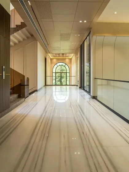 A view of the expansive corridor, where the polished marble floors reflect the light from the arched window. I designed this space to feel like a gallery, leading you through the home with a sense of grace and openness.