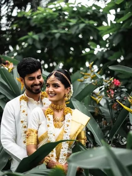 A beautiful, smiling portrait of the couple amidst the greenery. Their happiness is evident in this lovely South Indian wedding photo.