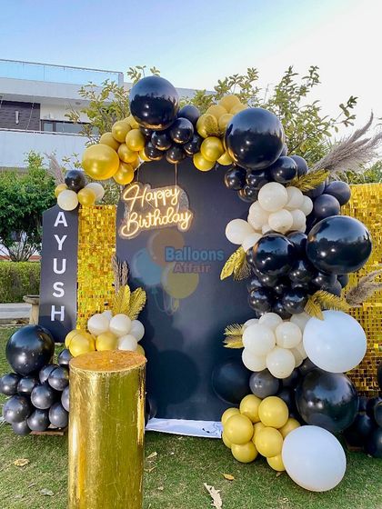 A close-up of the black and gold balloon arch against the shimmer wall.