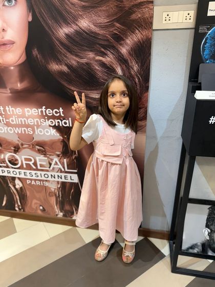 A proud young client showing off her new haircut with a peace sign. Her sleek, straight hair looks healthy and stylish.