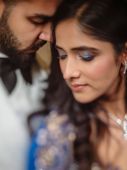An intimate close-up shot. The focus is on the beautiful blue eyeshadow and the soft, romantic feel of the moment.