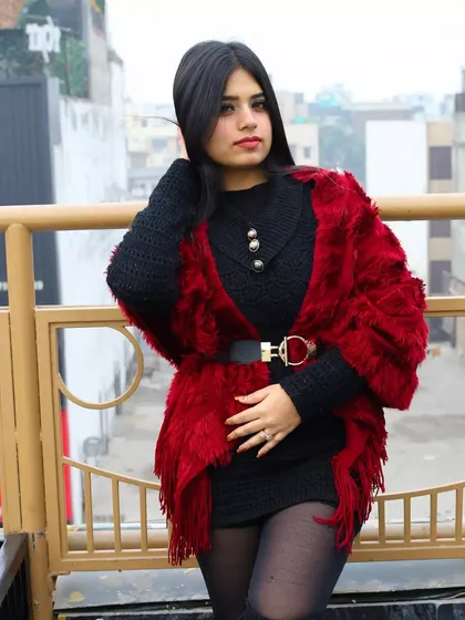 A full-body pose from the winter balcony shoot. This shot showcases the entire outfit, from the knit dress and fur wrap to the tights and boots, giving a complete fashion look.