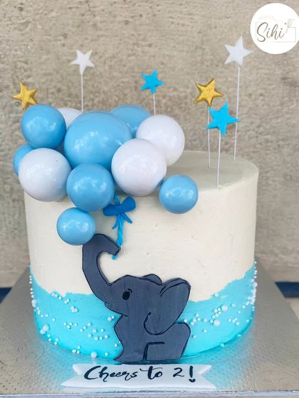 Ele-phantastic. A sweet and simple birthday cake featuring a cute elephant cutout holding a bunch of blue and white bauble balloons.