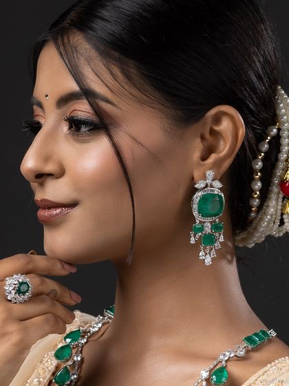 A detailed close-up of a model wearing an exquisite emerald and diamond earring set. This type of shot is perfect for high-end jewellery catalogue photography.