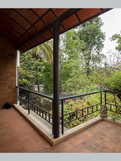 A wide view of the balcony, overlooking the lush green canopy of the garden below.