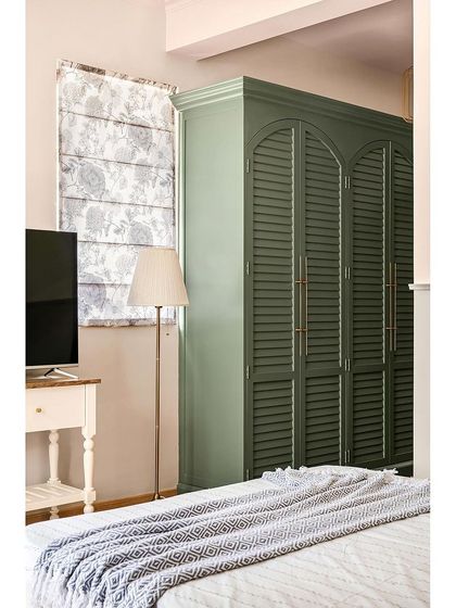 For the parents' room in this home, I aimed for a vintage feel. The louvered, arched closet in a muted pastel green adds elegance, while brass accents create a serene and classic atmosphere.
