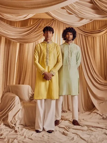 A portrait of two male models in elegant kurtas. Their grooming is impeccable, with a focus on natural-looking skin and neat hair, demonstrating the perfect polished look for any wedding function.
