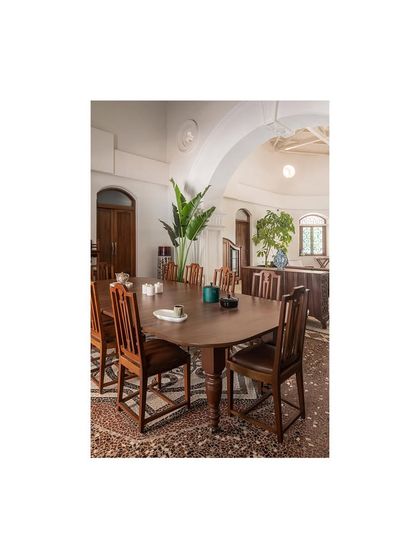 The formal dining area, featuring a large, restored wooden table set upon an intricate mosaic floor pattern. The space is designed for gathering, surrounded by the home's rich history.