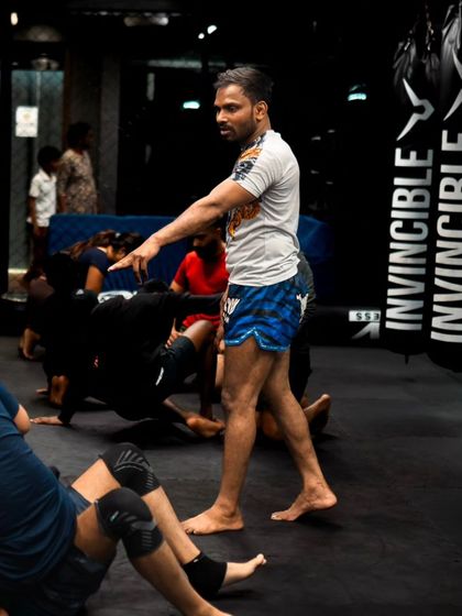 A coach oversees a class of students practicing their ground movements and drills.