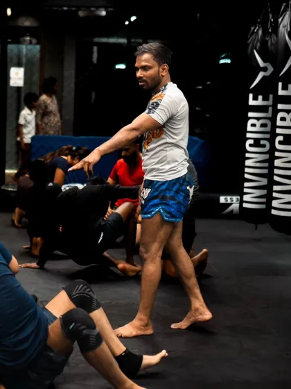 A coach oversees a class of students practicing their ground movements and drills.