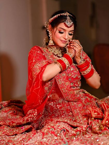 A beautiful seated portrait that lets the intricate red lehenga spread out in all its glory.