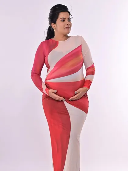 A modern maternity look in a vibrant, form-fitting gown. The makeup is clean and fresh, with a simple ponytail to keep the look contemporary and chic.