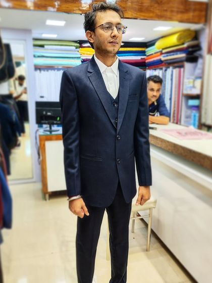 A client looking sharp and confident in a classic navy blue three-piece suit. This timeless look was tailored using imported lustre fabric for a perfect fit and a subtle sheen.