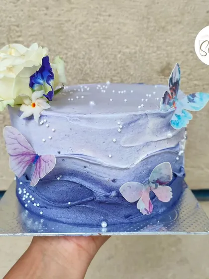 A pretty blueberry butterfly cake with a beautiful purple ombre wave effect. The design is completed with fresh flowers and delicate edible butterflies.