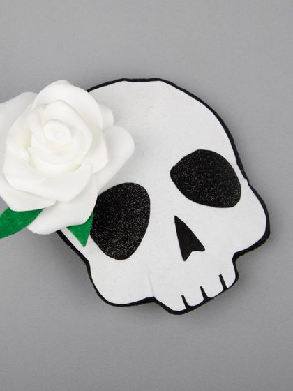 A Halloween-themed hair clip featuring a skull with a white rose.