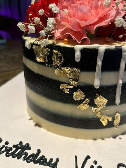 A close-up of the gold leaf and white chocolate drip on the striped cake.