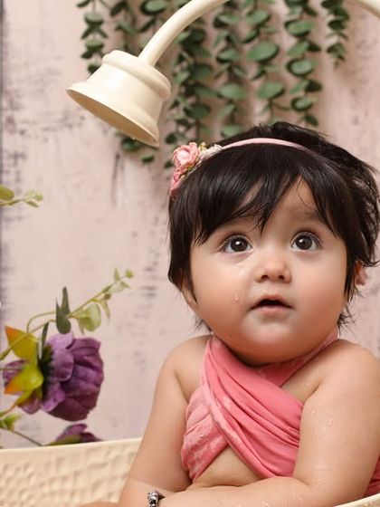 This little one is looking up with wide-eyed wonder during her bath time photoshoot. The combination of soft lighting and floral elements creates a sweet and artistic portrait.