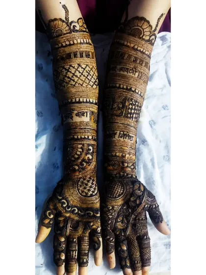 This design features Marathi script, with 'आई बाबा' (Aai Baba - Mom Dad) and 'मितवा' (Mitwa - Partner) written on the arms. It's a beautiful way to honor family in the bridal mehandi.