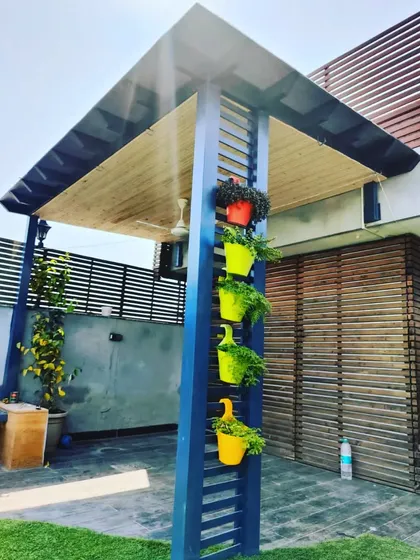 A unique blue pergola with a slatted pillar that doubles as a vertical planter holder, adding a playful and colorful element to the garden.