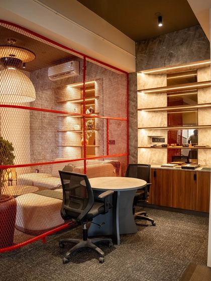 This image shows a semi-private discussion area next to the lounge. The red mesh partition creates a visual boundary without completely closing off the space, encouraging spontaneous collaboration.