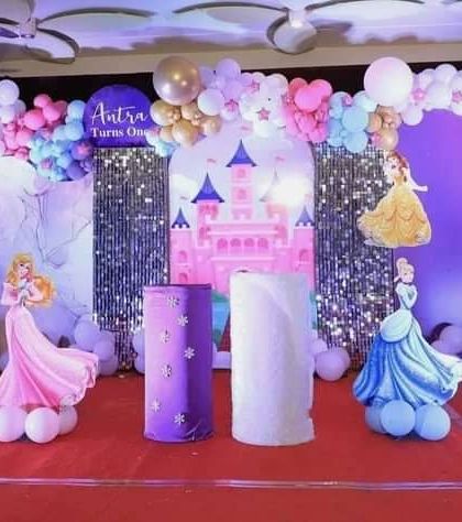 A grand Disney Princess theme for a first birthday, featuring cutouts of multiple princesses and a castle backdrop.