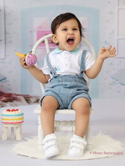 A toddler boy gives a mighty roar in our pastel-colored candy shop theme, holding a toy ice cream cone.