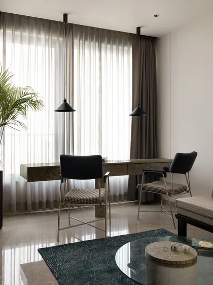 The multipurpose room includes a clean, clutter-free workstation for two. The floating desk is placed in front of a large window to maximize natural light, creating a serene and productive environment.