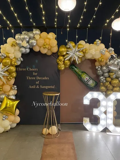 Celebrating 'Three Cheers for Three Decades' with this custom 30th milestone party. The setup includes a personalized backdrop, gold and silver balloon arches, and large light-up marquee numbers.