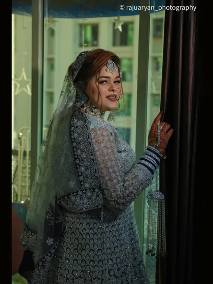 A candid shot of the bride looking back over her shoulder. The soft light from the window illuminates her profile and the delicate details of her veil.