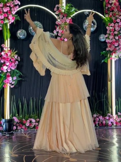 A back view of my beautiful tiered gown for a Sangeet night, with a floral and disco ball backdrop.