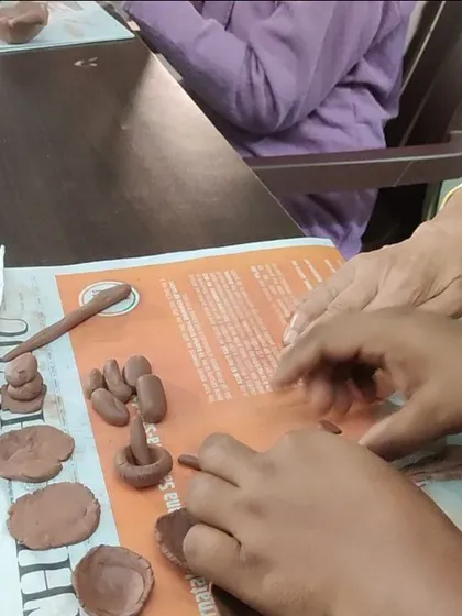 Hands of different generations working together with clay. These sessions can be a beautiful point of connection, where caregivers and seniors share a creative, non verbal experience.